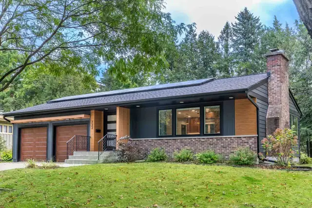 Mid-century modern ranch remodel in Madison, WI with a new dark roof, brick chimney and wood-trimmed entry