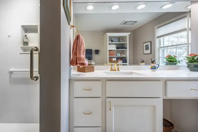 Aging-in-place bathroom remodel in Maple Bluff, WI with a brass grab bar, white cabinetry and open display shelving