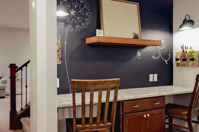 Built-in craft desk with a wood shelf, granite counter and a dark accent wall