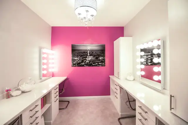 Dressing room renovation in Madison, WI with white built-in vanities, lighted mirrors and a pink accent wall