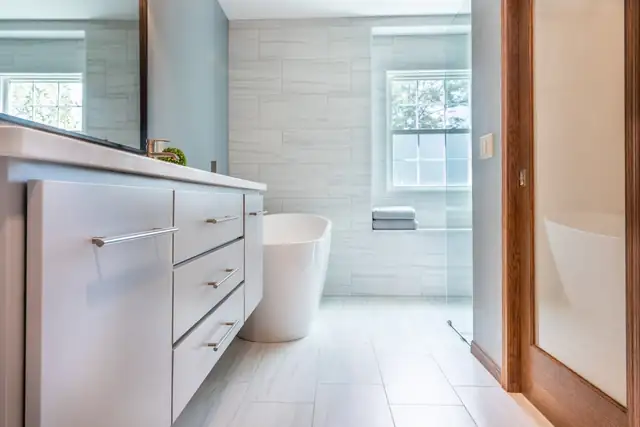 Contemporary bathroom remodel in Madison, WI with a freestanding tub, white flat-panel vanity and large-format wall tile