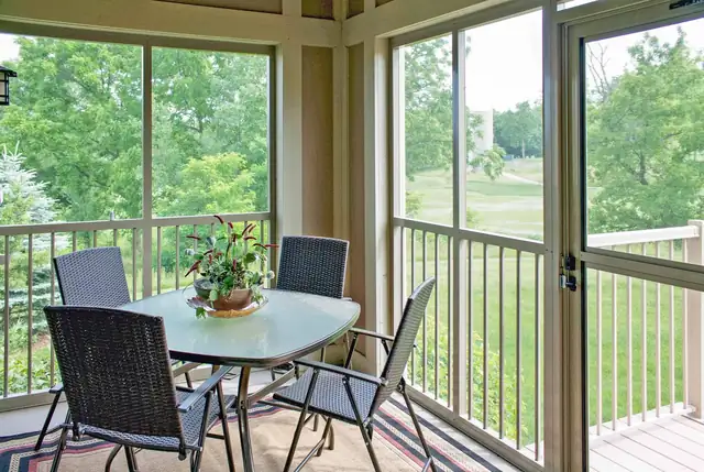 Screened porch with a dining set overlooking trees in a Madison condominium renovated by Degnan